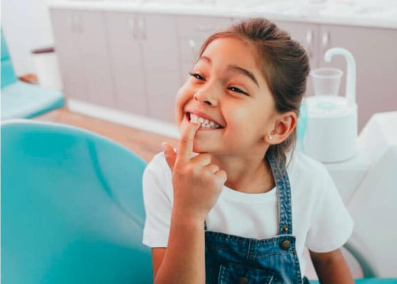 Young girl pointing to her teeth at dentist office.