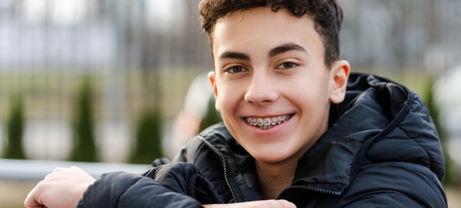 Boy with jacket smiling with braces.